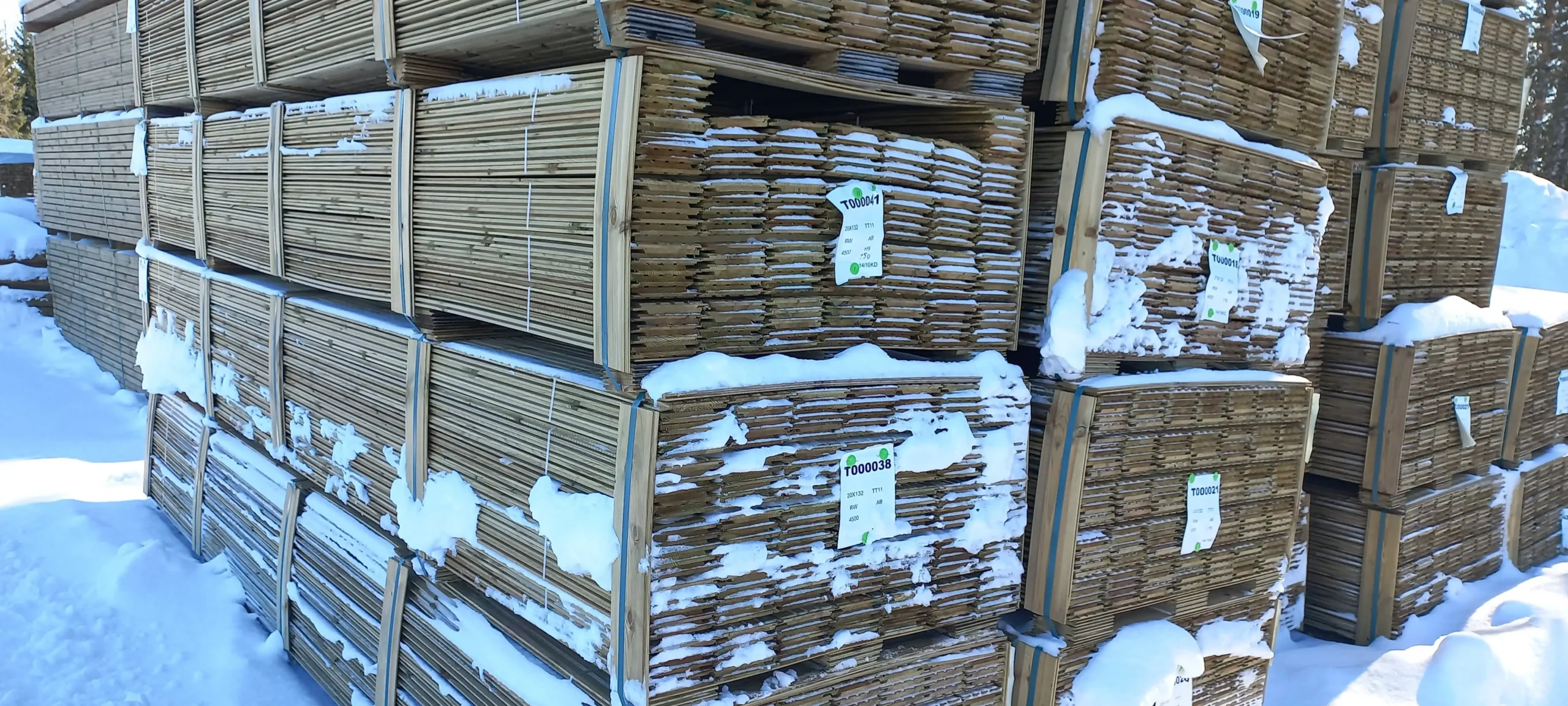 Stock de lames de bois entreposées sous la neige, prêtes pour livraison par PéSim.